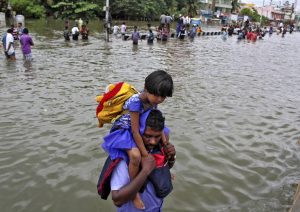 A man carries a girl through a flooded road in Chennai